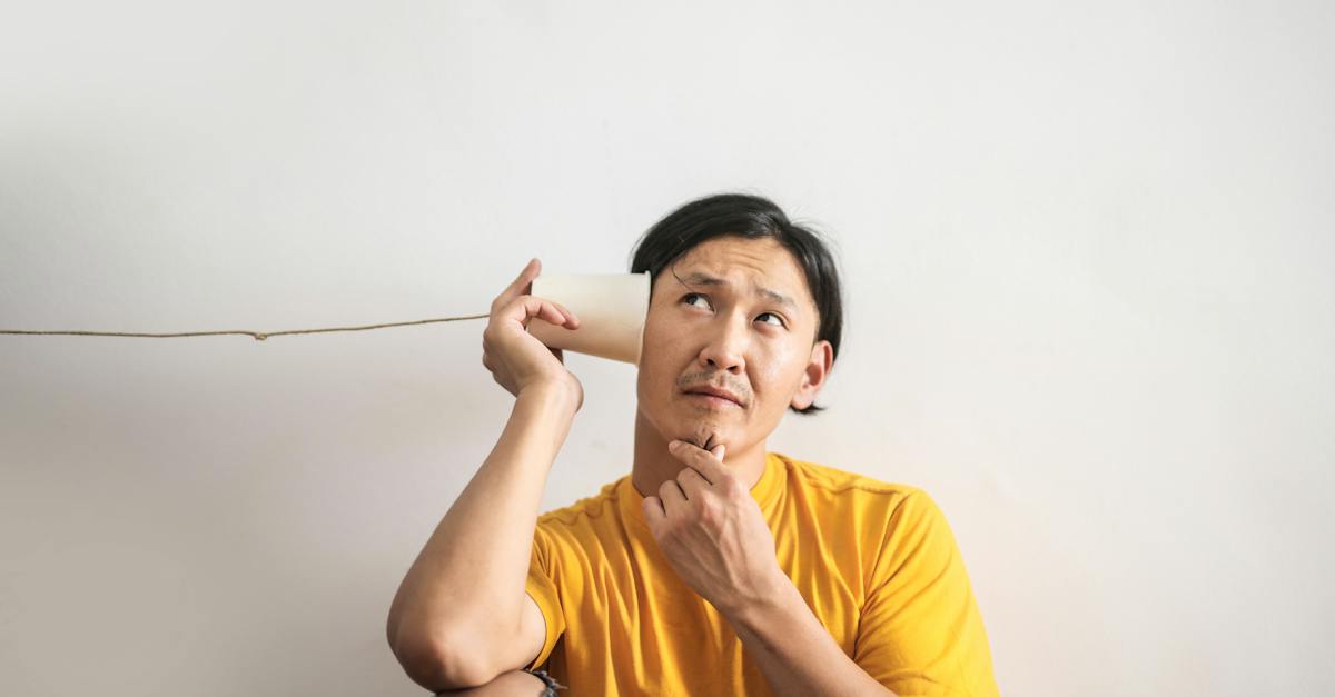 nachdenklicher ethnischer mann der im pappbechertelefon antwortet